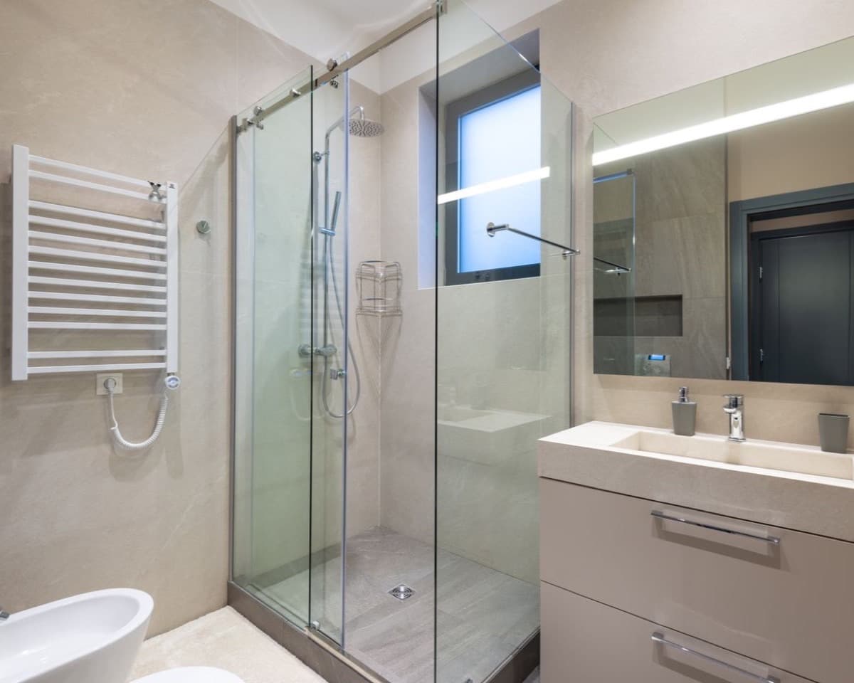 Cam duşakabinli, açık renk seramikli modern banyo
